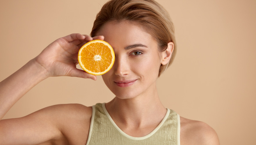 Femeie fericita cu o portocala in mana
